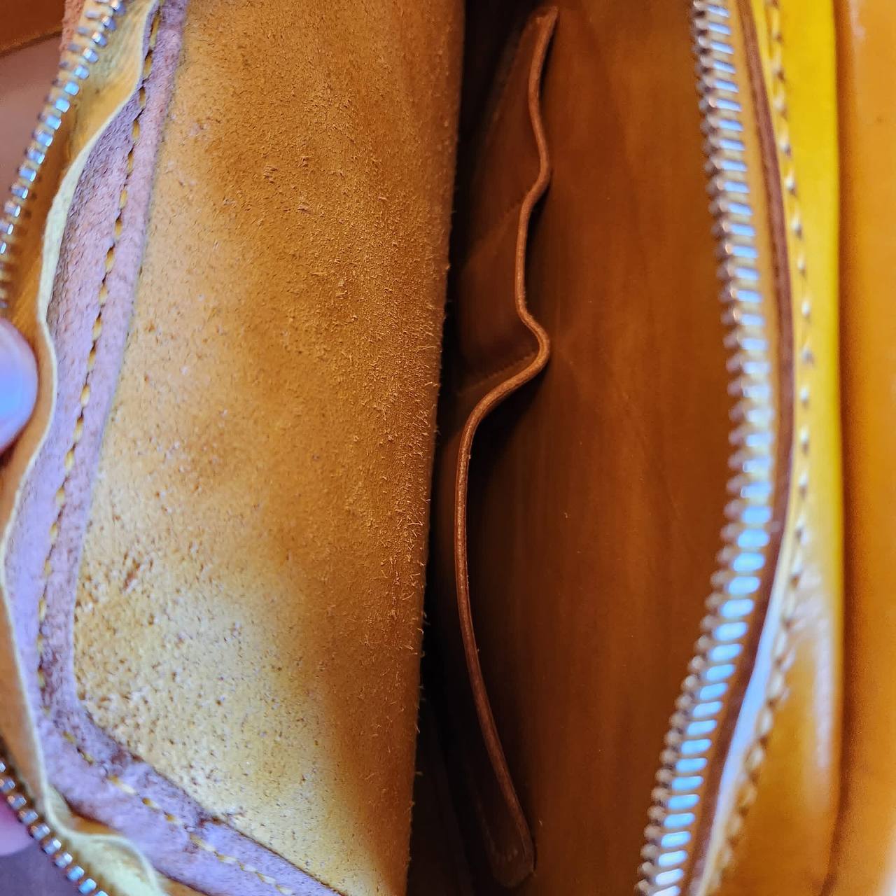 Interior detail of a handmade yellow leather purse with zippered pocket